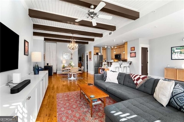 living room with ceiling fan with notable chandelier, beamed ceiling, and light wood-type flooring