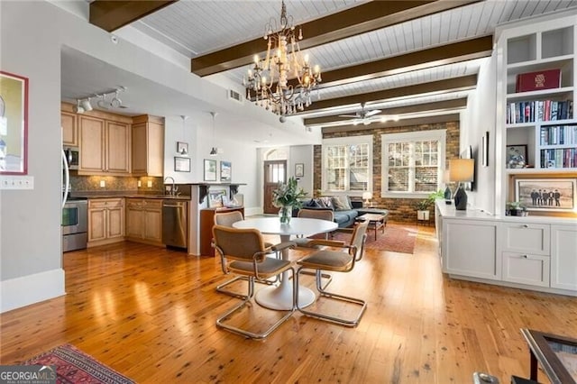 dining space with an inviting chandelier, sink, light hardwood / wood-style floors, and beamed ceiling