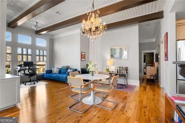 dining area with beamed ceiling, a chandelier, and light hardwood / wood-style floors