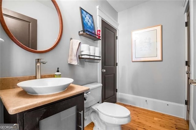 bathroom with hardwood / wood-style flooring, vanity, and toilet