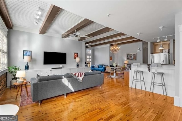 living room featuring ceiling fan with notable chandelier, beam ceiling, and light hardwood / wood-style floors