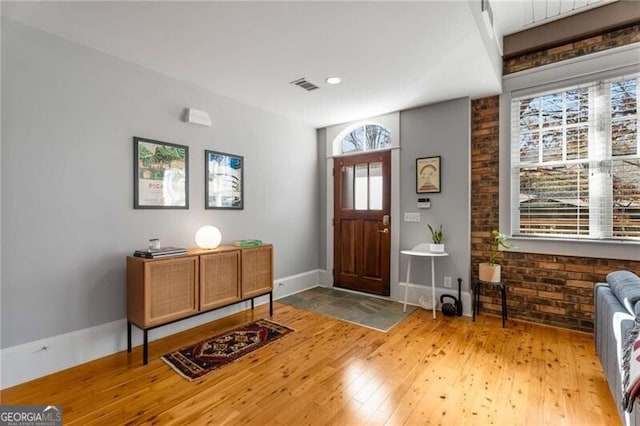 entrance foyer with light hardwood / wood-style flooring and brick wall