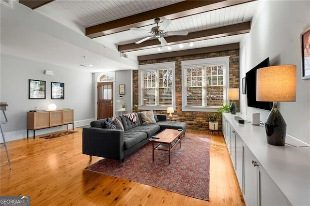 living room with beamed ceiling, brick wall, ceiling fan, and light hardwood / wood-style flooring