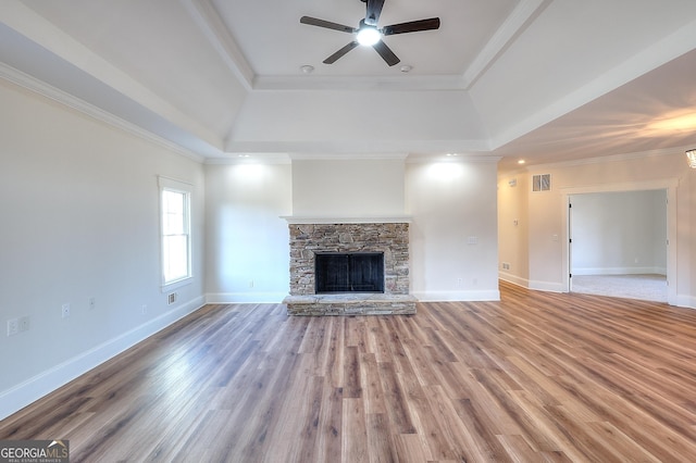 unfurnished living room with a fireplace, wood-type flooring, ceiling fan, a raised ceiling, and crown molding