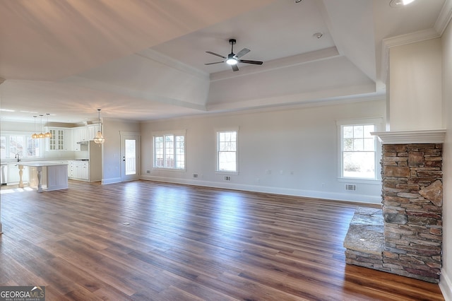 unfurnished living room featuring a raised ceiling, dark hardwood / wood-style floors, and a wealth of natural light