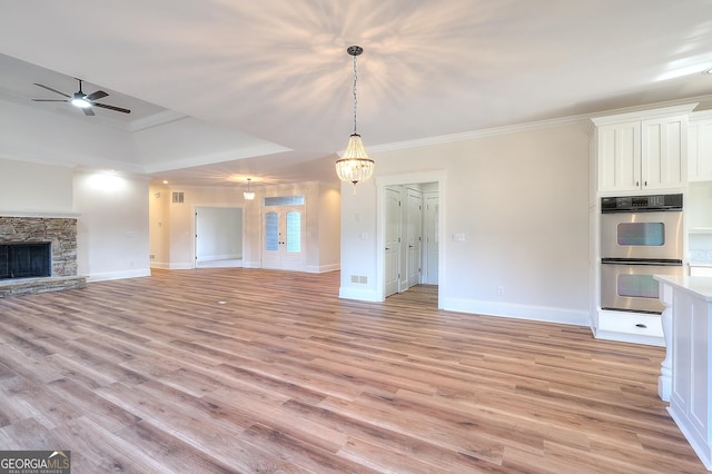 unfurnished living room featuring light hardwood / wood-style flooring, crown molding, a fireplace, and ceiling fan