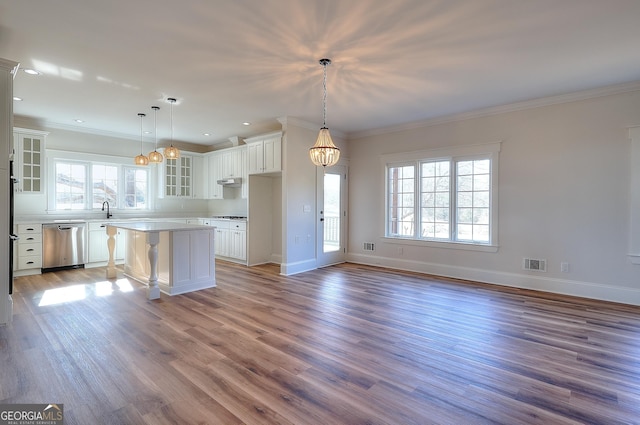 kitchen with a breakfast bar, hanging light fixtures, a center island, white cabinets, and stainless steel dishwasher