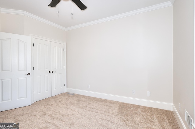 unfurnished bedroom with light carpet, crown molding, and a closet