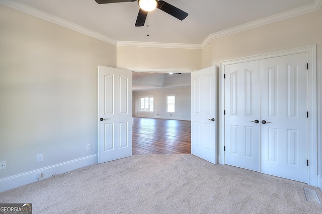 unfurnished bedroom with crown molding, a closet, ceiling fan, and carpet