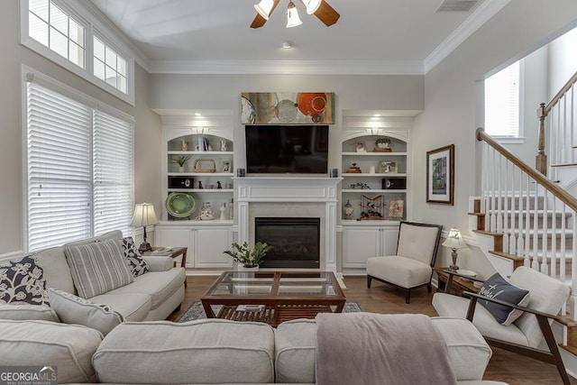 living room featuring crown molding, built in shelves, and plenty of natural light