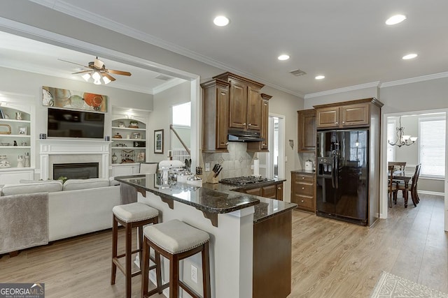 kitchen with a kitchen breakfast bar, dark stone countertops, black fridge with ice dispenser, and light hardwood / wood-style flooring