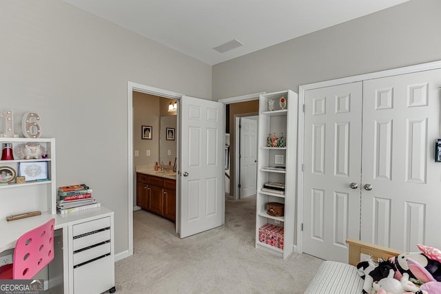 bedroom featuring ensuite bath, light colored carpet, and a closet