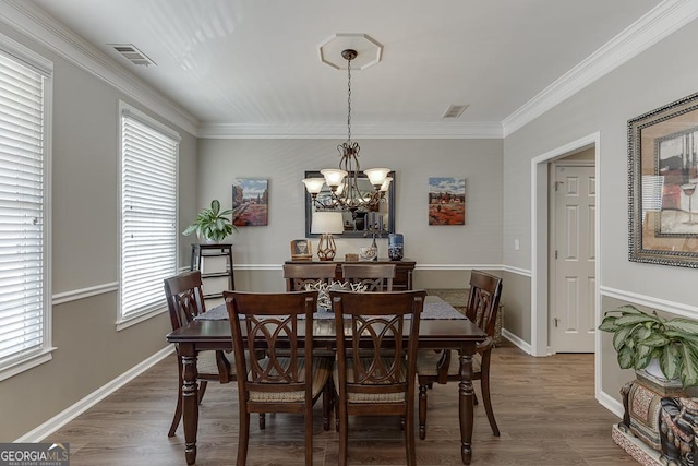 dining room featuring wood-type flooring, ornamental molding, and a chandelier