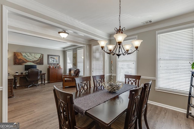 dining room with crown molding, light hardwood / wood-style floors, and a notable chandelier