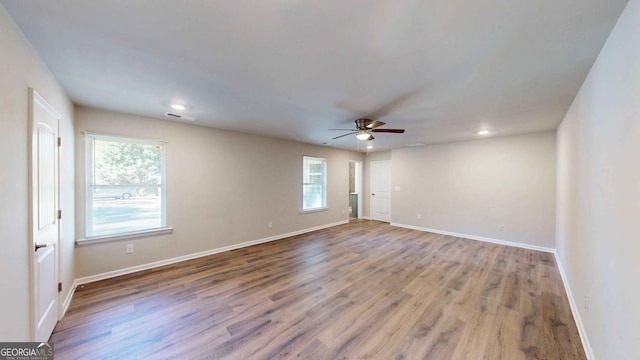 spare room with ceiling fan, a wealth of natural light, and light wood-type flooring