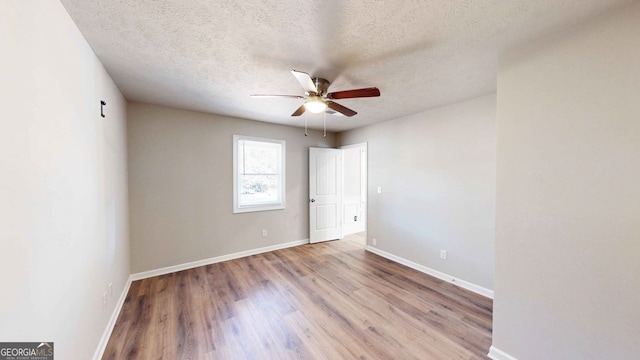 spare room featuring ceiling fan, light hardwood / wood-style flooring, and a textured ceiling