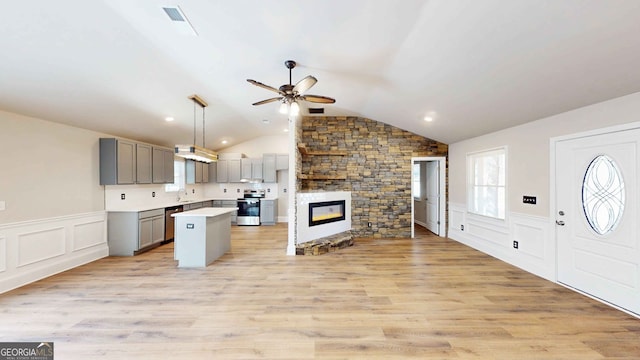 kitchen featuring decorative light fixtures, gray cabinets, a kitchen island, electric stove, and a fireplace