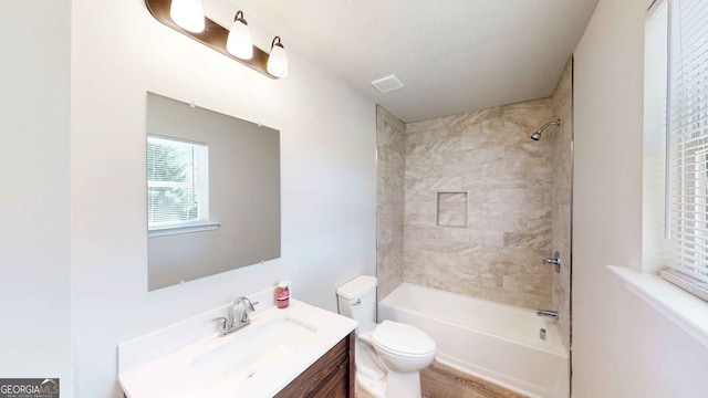 full bathroom featuring tiled shower / bath, vanity, and toilet