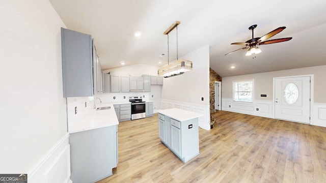 kitchen with lofted ceiling, sink, stainless steel electric range, hanging light fixtures, and a kitchen island