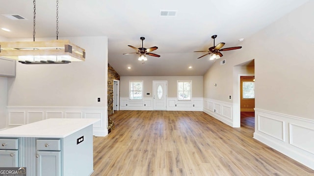 unfurnished living room with ceiling fan, vaulted ceiling, and light wood-type flooring