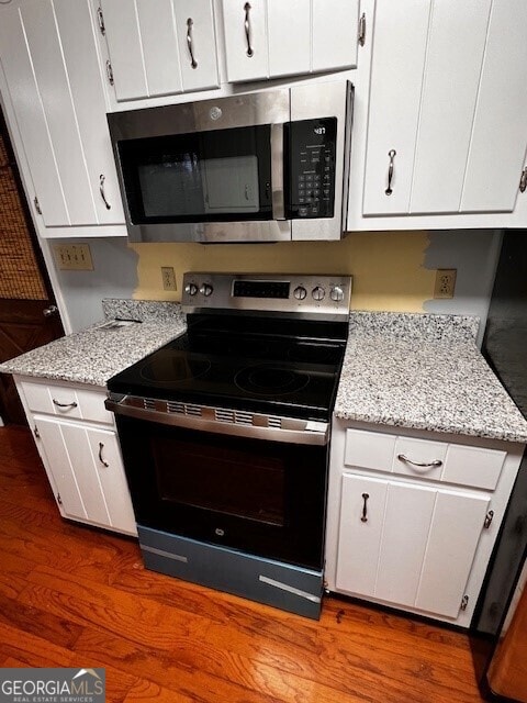 kitchen featuring white cabinetry, light stone countertops, stainless steel appliances, and dark hardwood / wood-style floors