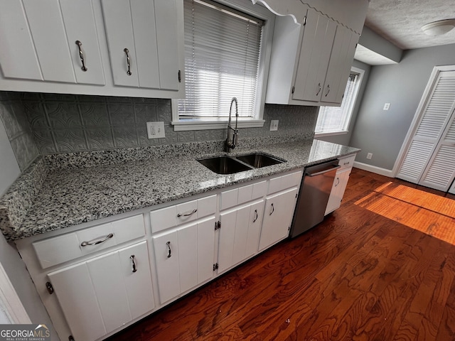 kitchen featuring tasteful backsplash, dishwasher, dark wood-style flooring, white cabinetry, and a sink