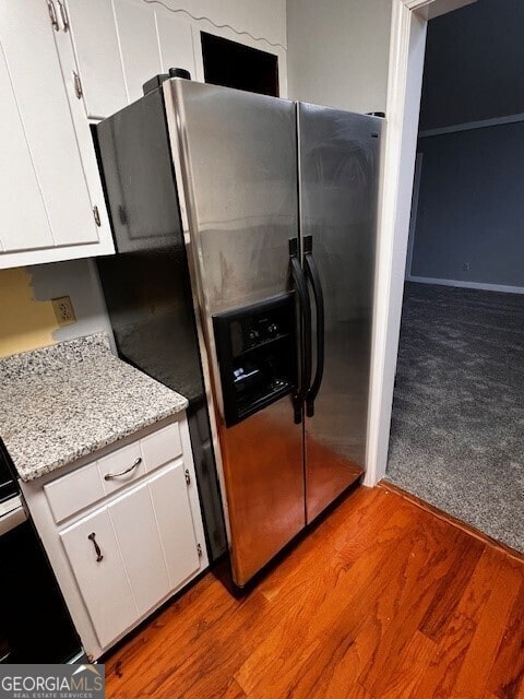 kitchen with stainless steel fridge with ice dispenser, light hardwood / wood-style floors, white cabinets, and light stone countertops