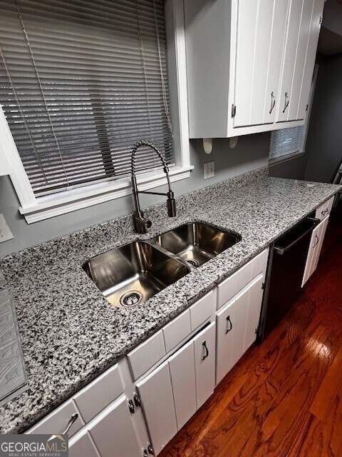 kitchen with dark hardwood / wood-style floors, black dishwasher, sink, white cabinets, and light stone counters