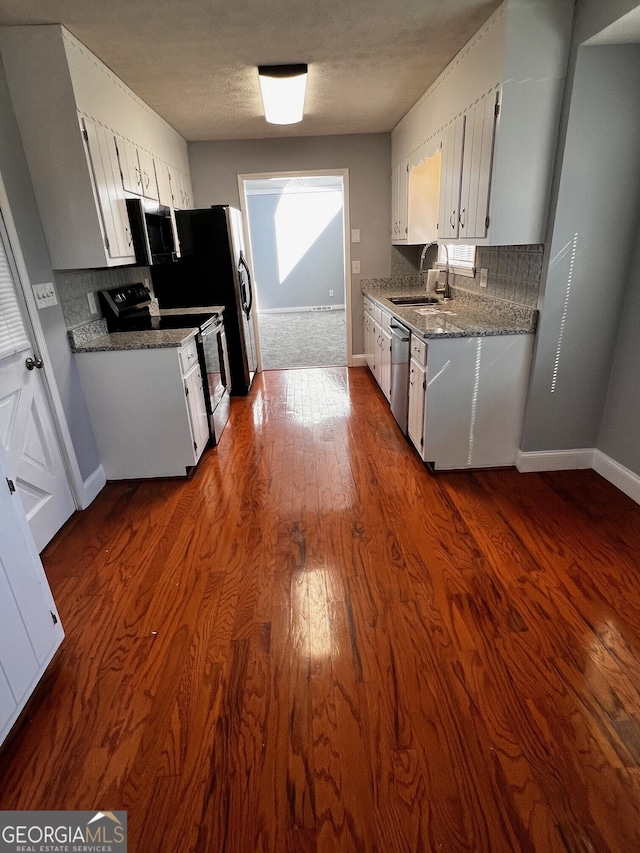 kitchen with stainless steel appliances, decorative backsplash, dark wood-type flooring, a sink, and baseboards