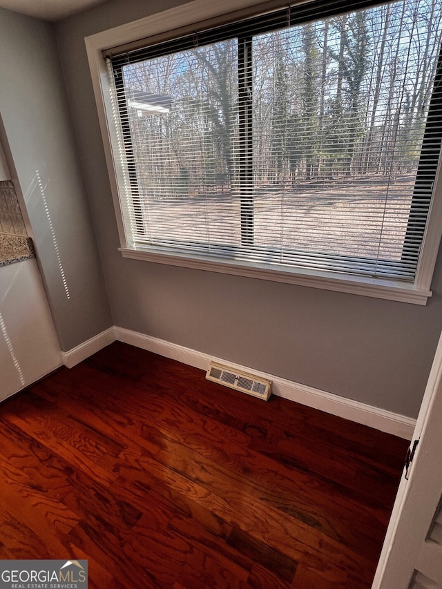 unfurnished dining area featuring baseboards, visible vents, and dark wood-style flooring