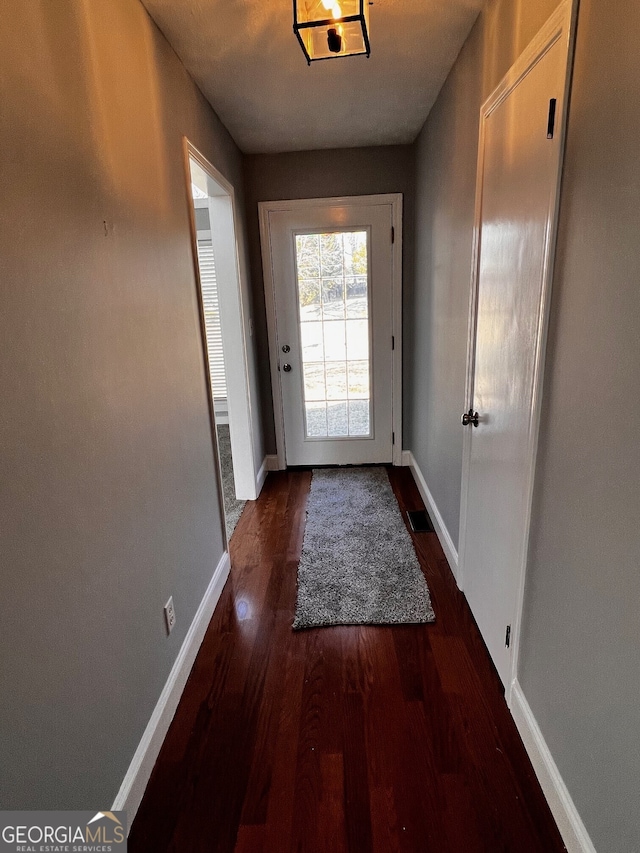 doorway with baseboards and wood finished floors