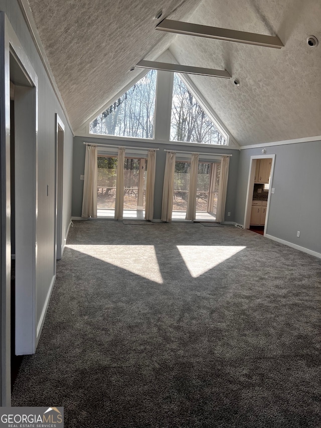 unfurnished living room featuring dark carpet, a wealth of natural light, high vaulted ceiling, and a textured ceiling