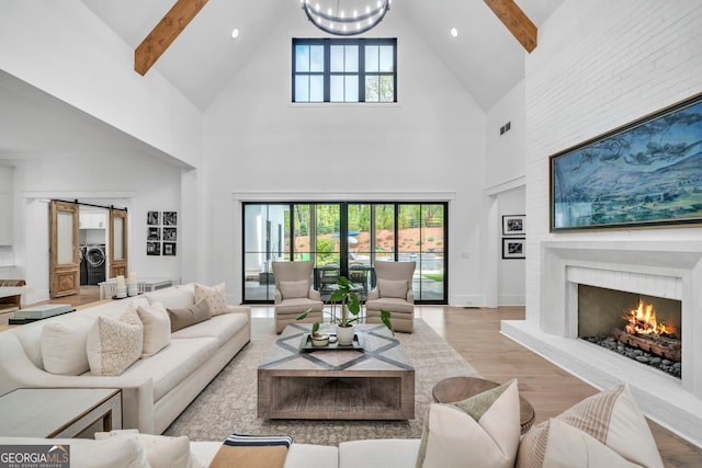 living room with a barn door, light wood-type flooring, and beam ceiling