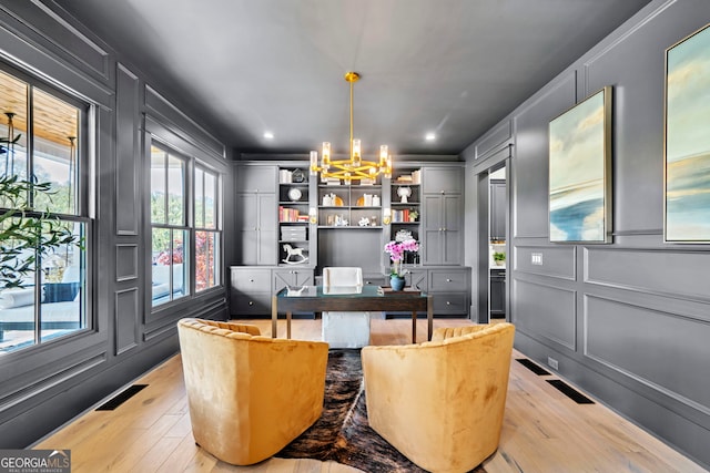 home office featuring an inviting chandelier and light hardwood / wood-style floors