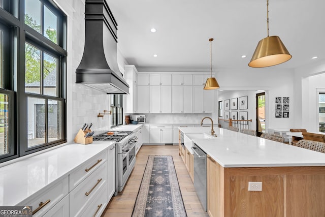 kitchen with sink, stainless steel appliances, white cabinets, decorative light fixtures, and custom exhaust hood