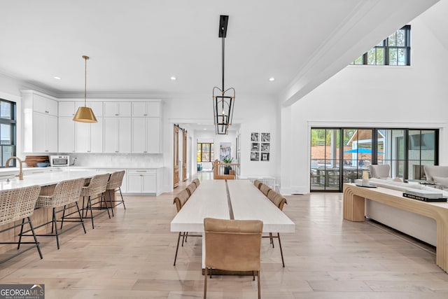 dining area featuring crown molding, a chandelier, sink, and light hardwood / wood-style flooring