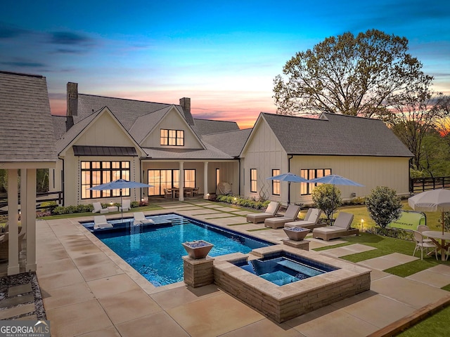 back house at dusk with a pool with hot tub and a patio area