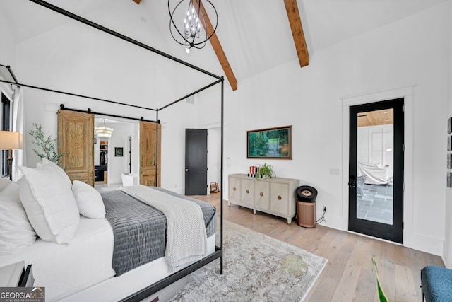 bedroom with an inviting chandelier, high vaulted ceiling, beamed ceiling, a barn door, and light wood-type flooring