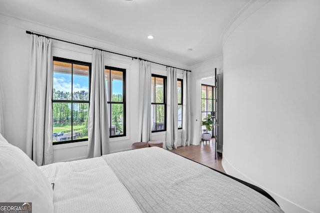 bedroom featuring multiple windows, ornamental molding, and hardwood / wood-style floors