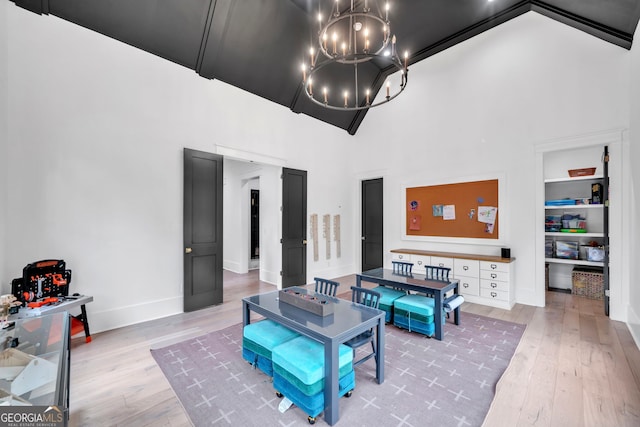 living room featuring a notable chandelier, built in shelves, wood-type flooring, and a high ceiling