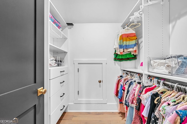 walk in closet with light hardwood / wood-style flooring