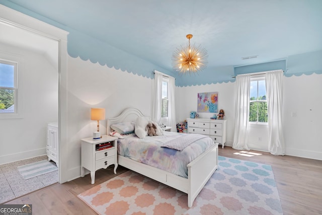 bedroom with a notable chandelier and light wood-type flooring