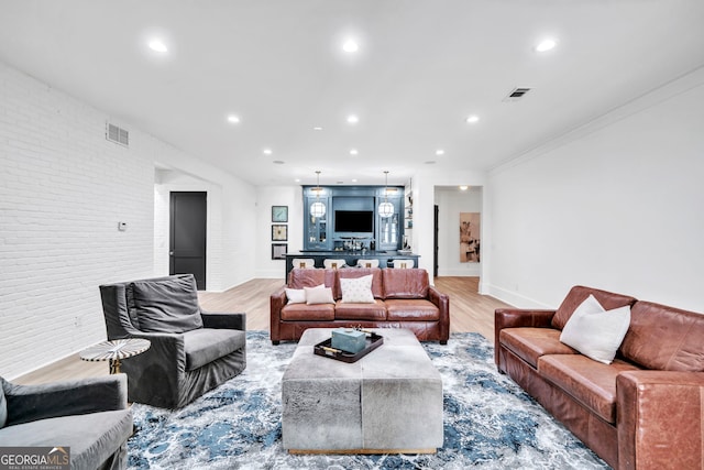 living room with brick wall and light hardwood / wood-style floors