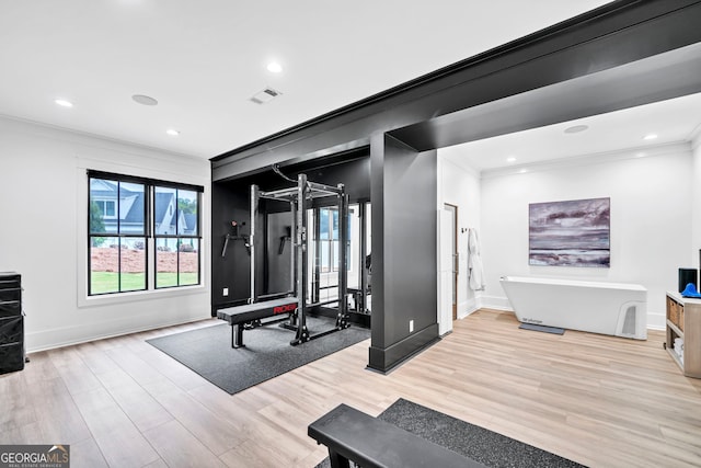 exercise room featuring crown molding and light hardwood / wood-style floors