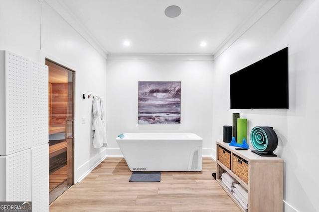 bathroom featuring a washtub, crown molding, and wood-type flooring