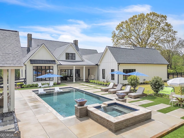 back of house with a patio area and a pool with hot tub