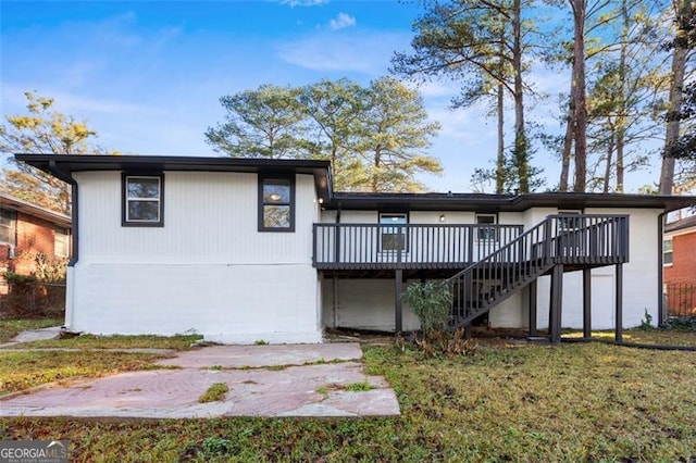 back of property with a wooden deck and a lawn