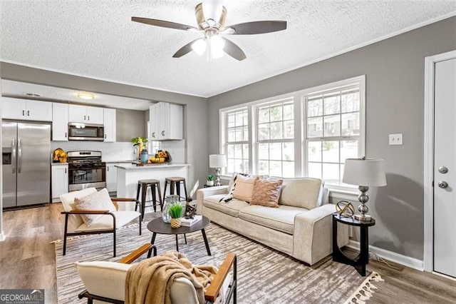 living room with hardwood / wood-style floors, a textured ceiling, ornamental molding, and ceiling fan