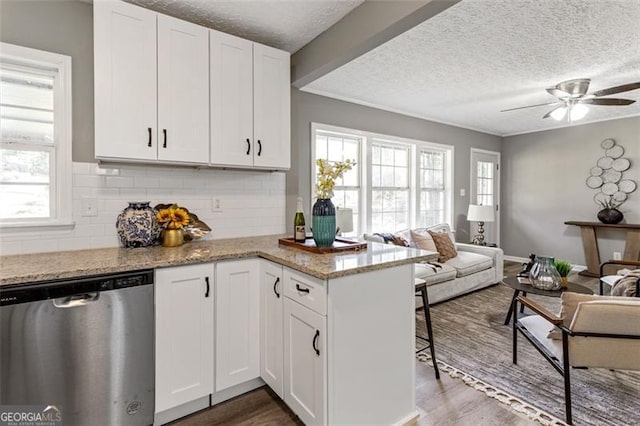 kitchen featuring light stone counters, white cabinets, wood-type flooring, and dishwasher