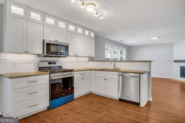 kitchen featuring white cabinetry, appliances with stainless steel finishes, sink, and light wood-type flooring